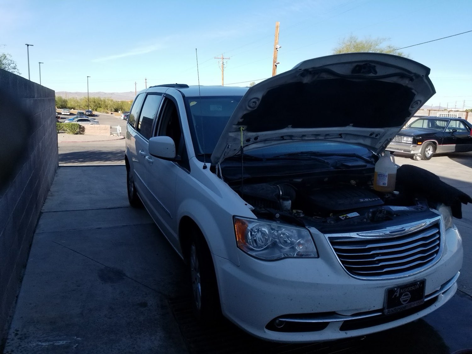 Minivan with the hood up for A/C and cooling system service