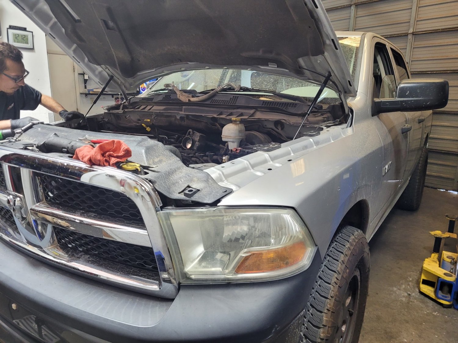 Autoworks technician diagnosing a pickup with the hood raised in the shop