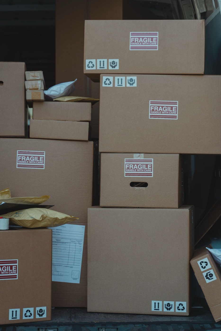 Cardboard moving boxes labeled Fragile — Handle With Care, neatly stacked inside a van