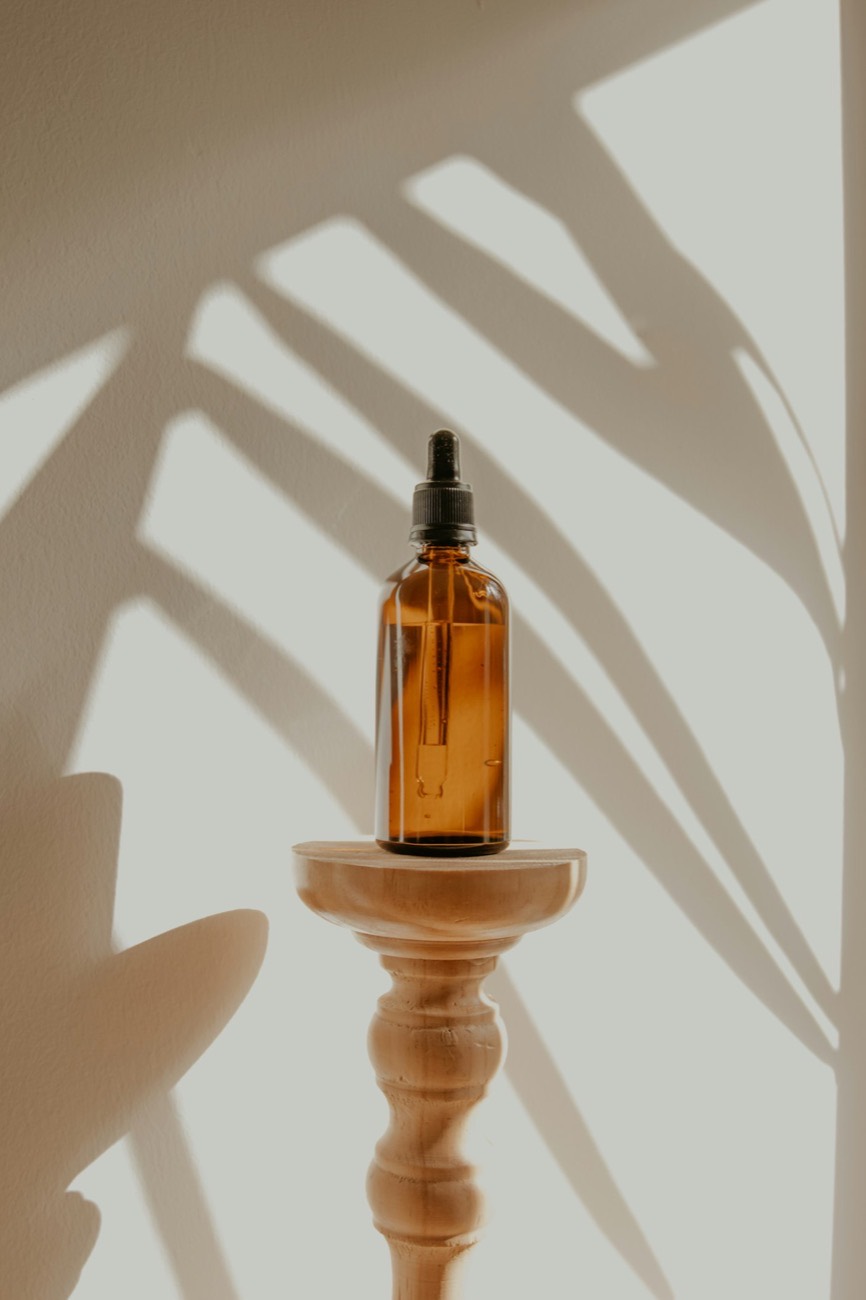 An amber bottle of massage oil in soft, dappled light