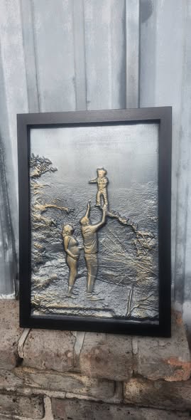 Sculpted relief art panel of a family at the shore, framed in black