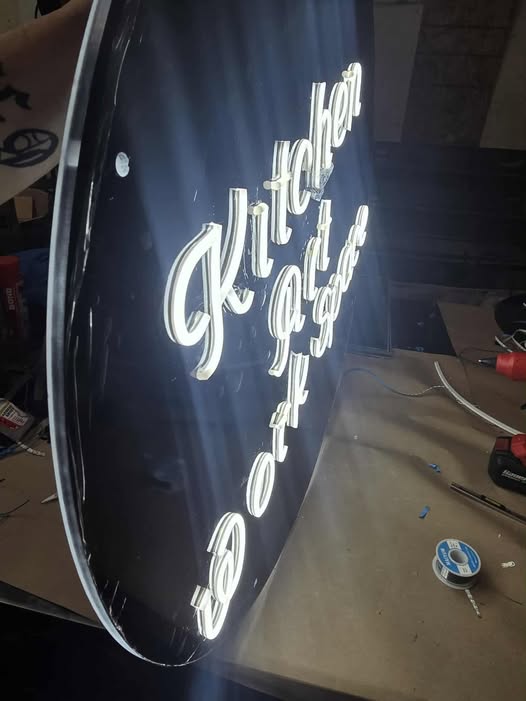 Custom faux-neon script sign being wired on the bench