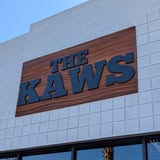 Wood-look storefront sign installed for The Kaws on a white brick building